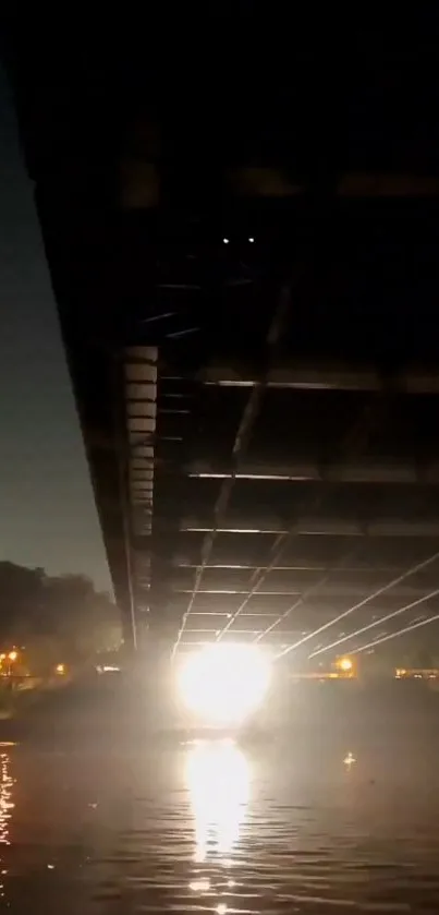 Night view under bridge with glowing light reflection on water surface.