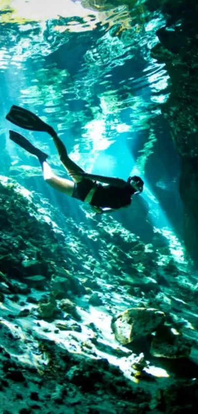 Diver swimming underwater with clear blue waters and rocks.