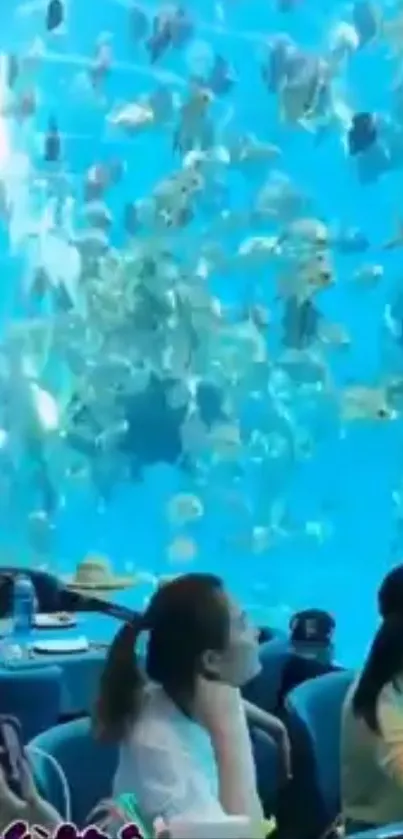 Dining in aquarium with blue water and vibrant fish.