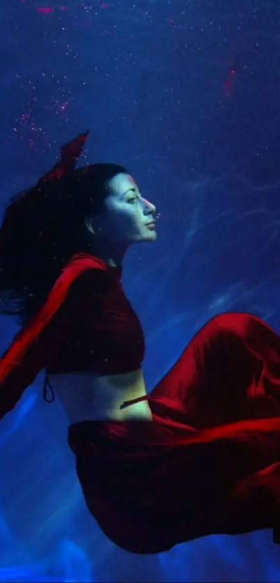 Woman in red dress underwater with deep blue background.