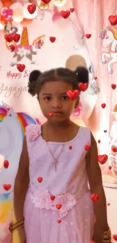 Girl in pink dress at unicorn-themed birthday party with hearts.