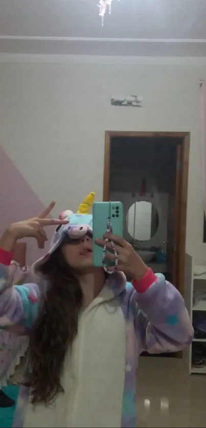 Person in a unicorn onesie taking a mirror selfie in a pastel-colored bedroom.