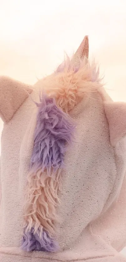 Person wearing unicorn hoodie against a soft pink sky.