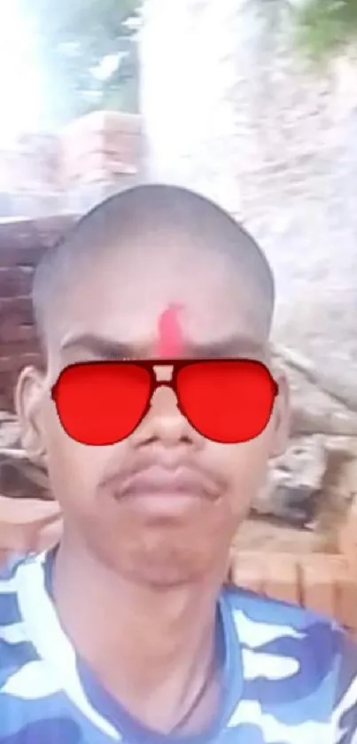 Person with red sunglasses and camouflage shirt against a brick background.