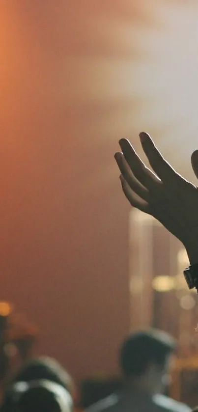 Hand reaching up at a live concert with vibrant lighting.