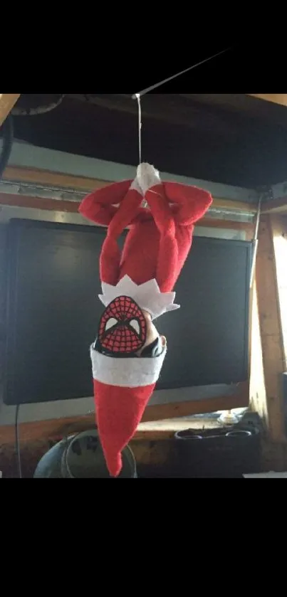 Upside-down Santa elf with superhero theme hanging as decoration.