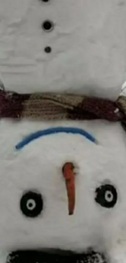 Upside down snowman with scarf in snow.