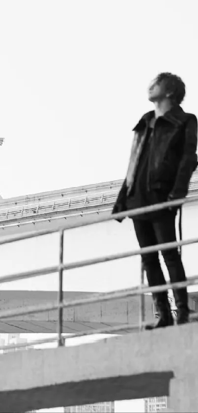 Monochrome photo of person standing on urban bridge.