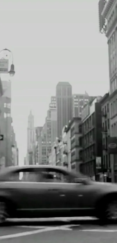 Black and white cityscape with moving car and tall buildings.