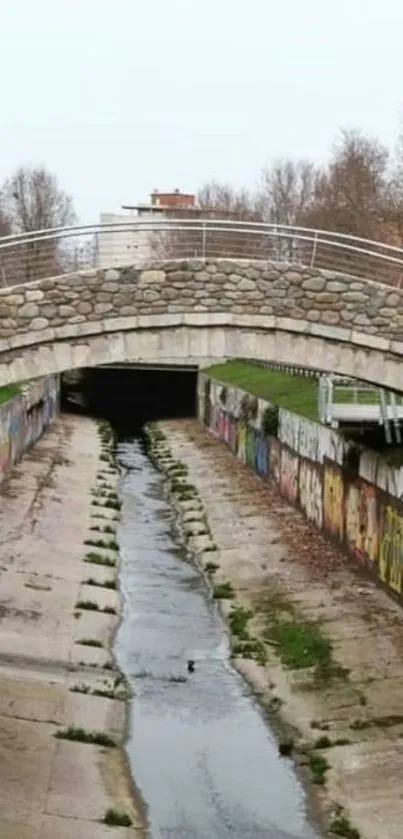 Urban scene with stone bridge and graffiti-lined canal.