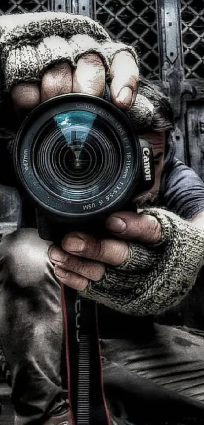 Close-up of a camera lens held by a person wearing gloves in an urban setting.