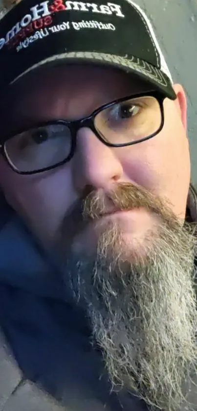 Urban casual portrait of a bearded man with glasses and a hat.