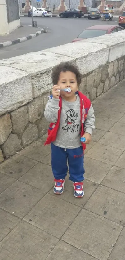 Child in urban setting with red jacket and blue shoes.