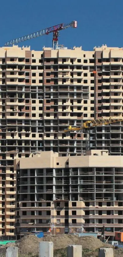 High-rise building under construction with cranes against a blue sky.