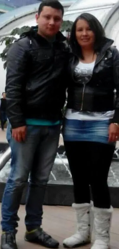 Couple posing by a fountain with modern architecture background.