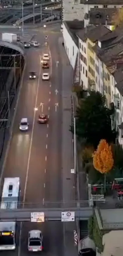 Aerial view of a city street at dusk with cars and buildings.