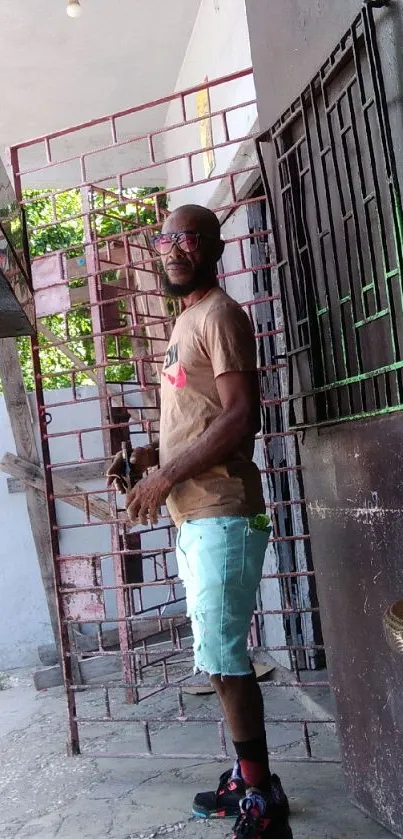 Man in casual attire by a rustic gate.