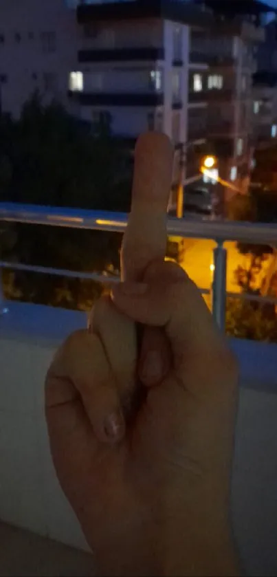 Hand showing gesture against urban night scenery.