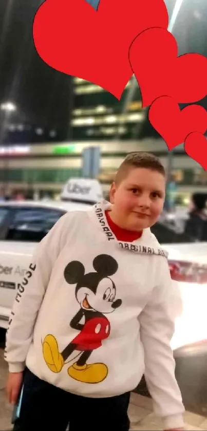 Child with cartoon shirt and hearts in city night scene.