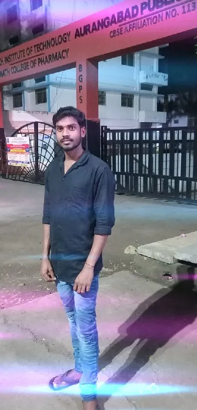 Man standing in front of a college campus at night.