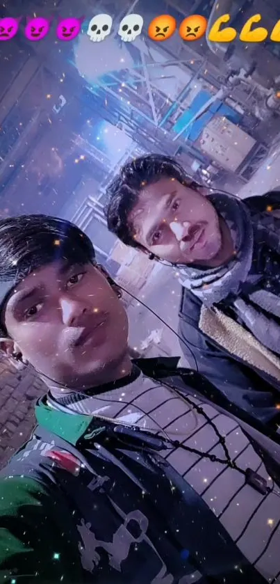 Two friends taking a selfie at night with emojis in the urban backdrop.