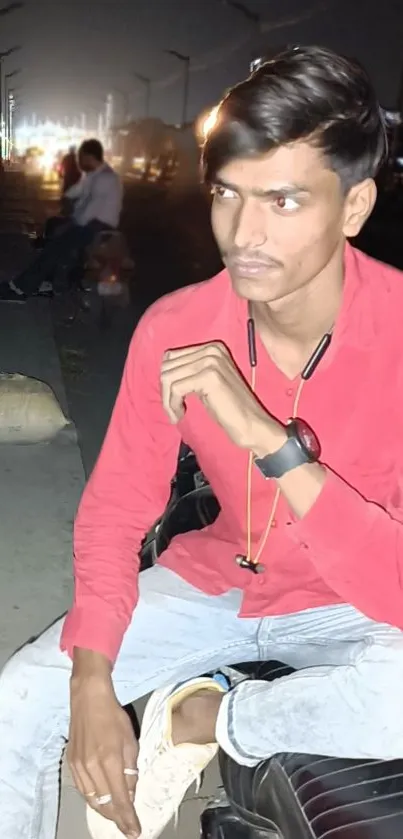 Urban portrait of a young man in a red shirt at night.