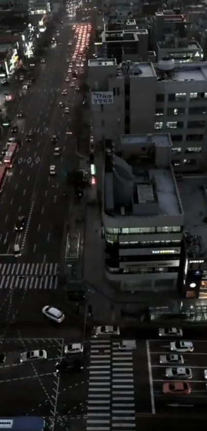 Aerial view of an urban street at night with vibrant city lights and traffic.