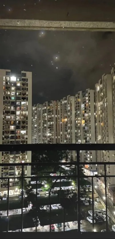 Night view of city skyline from a high-rise balcony, illuminated by city lights.