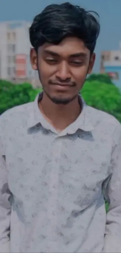 Portrait of a person outdoors with greenery and an urban backdrop.