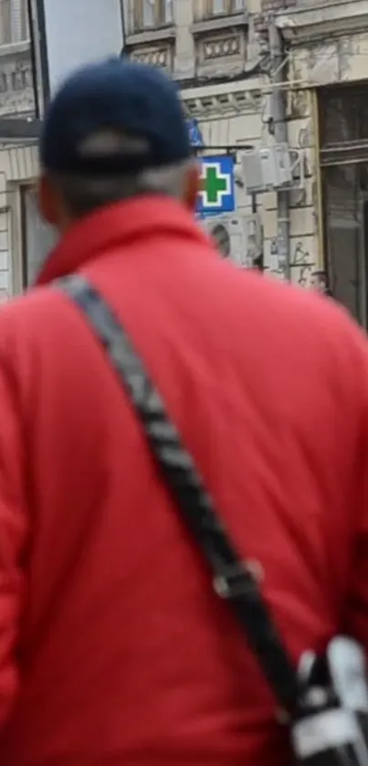 Person in red jacket walking in urban street.