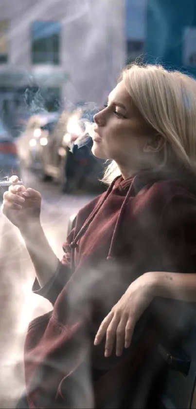 Woman in burgundy hoodie leaning on car, smoking in an urban setting.