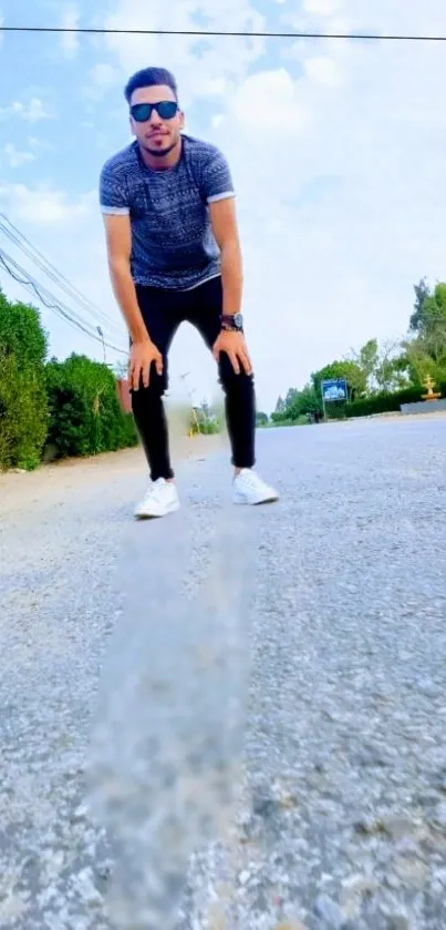 Stylish person on a sunlit road with trees and blue sky.