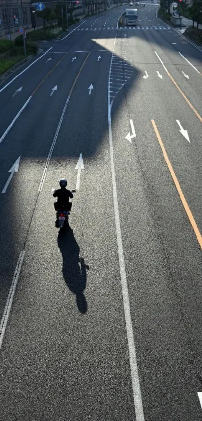 Cyclist on empty urban road casting a long shadow.