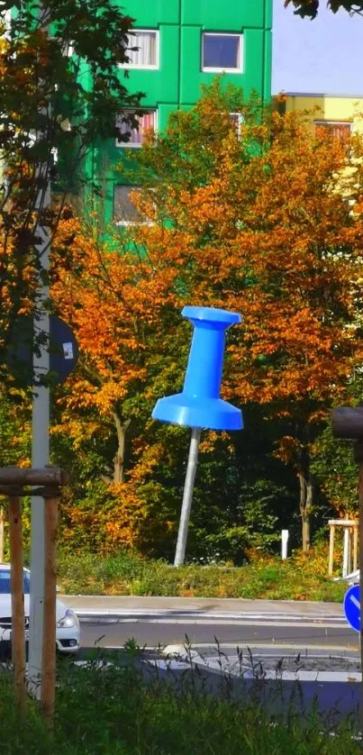 Urban scene with a giant blue pushpin and autumn foliage.