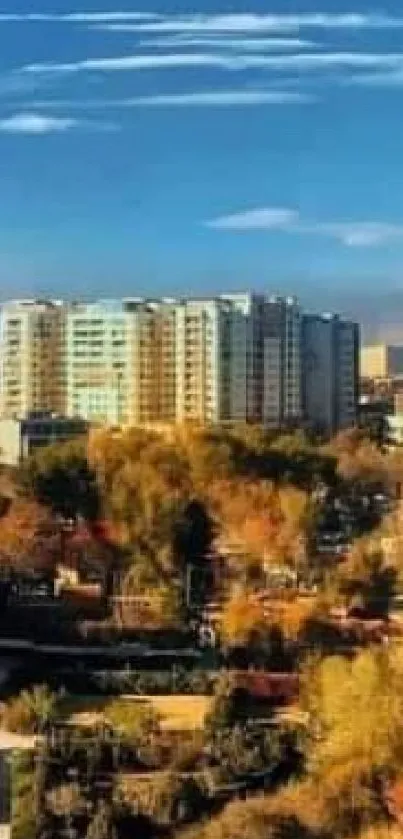 Mobile wallpaper of urban skyline with autumn trees below a blue sky.