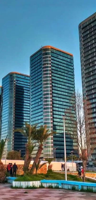 Skyscrapers glowing at sunset in urban park.