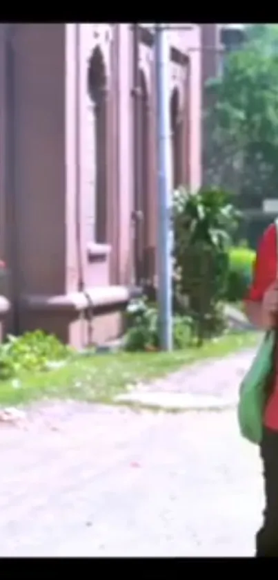 Stylish person walks by brick building on a sunny green street.