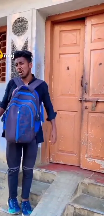 Young man with backpack at orange door.