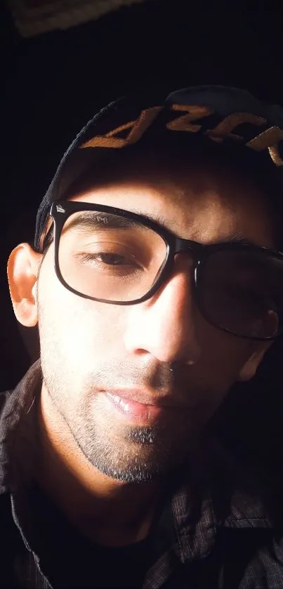 Portrait of a man in glasses and cap with dramatic lighting.