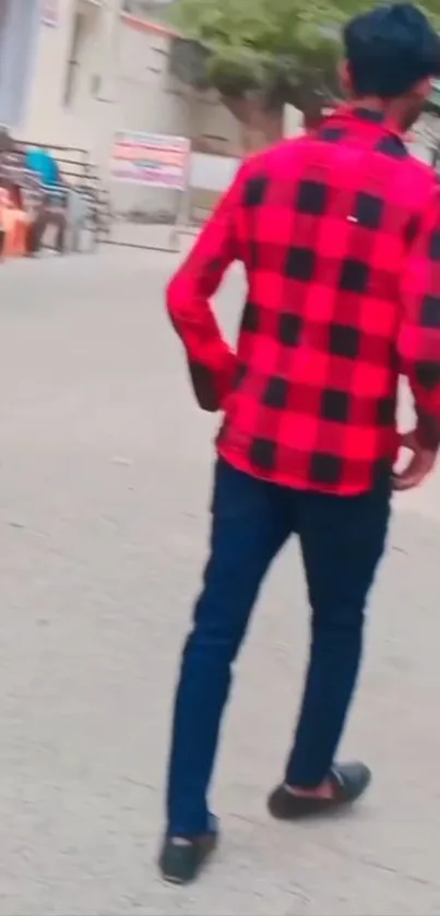 Person in red plaid shirt walking in city street.