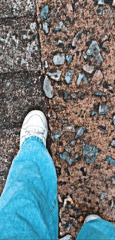 Urban walkway with stones and denim jeans in view.