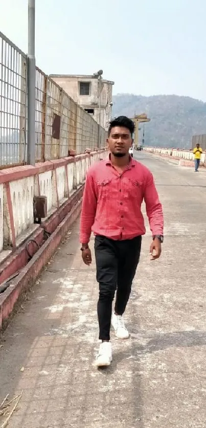 Man in red shirt walking on urban walkway.