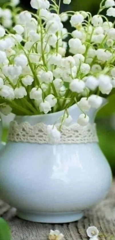 Vase with Lily of the Valley flowers surrounded by greenery.