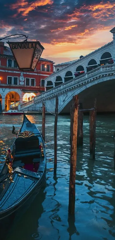 Venetian gondola at sunset with vibrant sky and historic bridge.