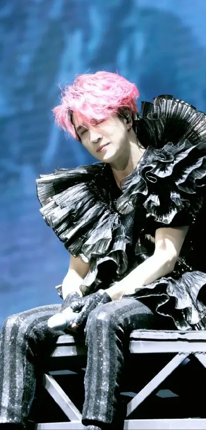 Artistic stage performance with pink hair and vibrant backdrop.