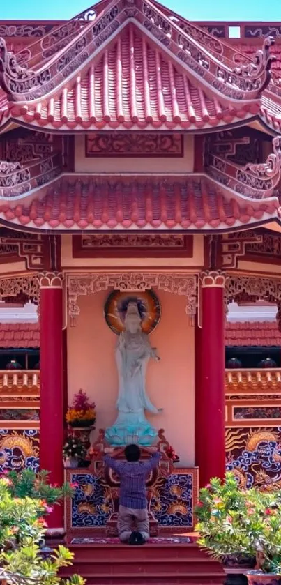 Vibrant red Asian temple with statue and greenery.