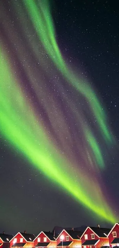 Aurora Borealis over red cottages with starry sky.