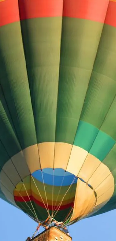 Vibrant green hot air balloon soaring in clear blue sky.