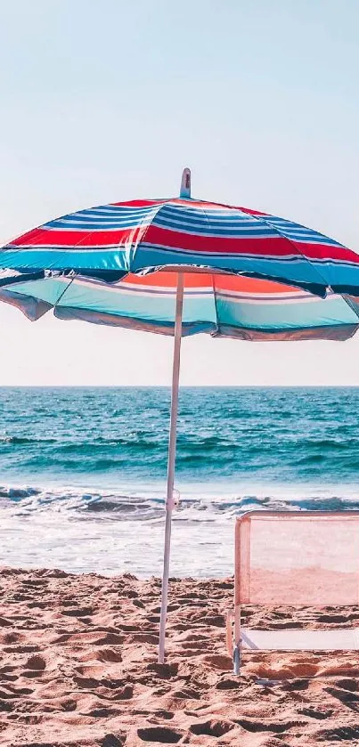 Vibrant beach with colorful umbrella and chair by the ocean.