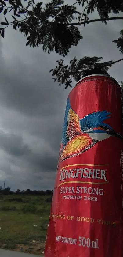 Vibrant red beer can against a dramatic outdoor background.